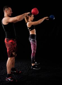 man and woman doing kettlebell swings for a muscle workout